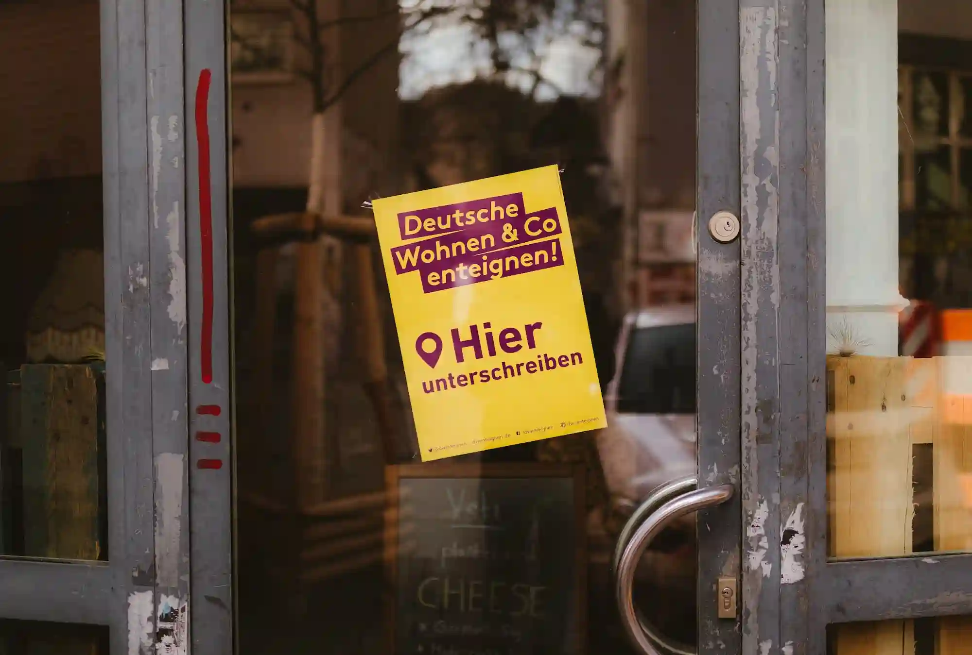 Eine Glastür, an der ein Flyer klebt. Auf dem Flyer steht: „Deutsche Wohnen & Co enteignen! Hier unterschreiben“